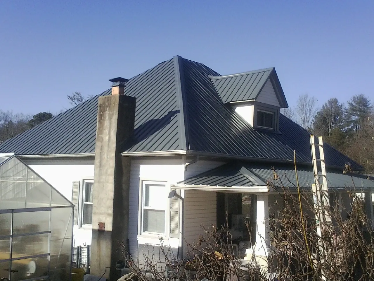 Dark blue standing seam metal roof on a white farmhouse with dormer — Slate & Tile Roof Repair by Roofing Brothers in South Lake Tahoe