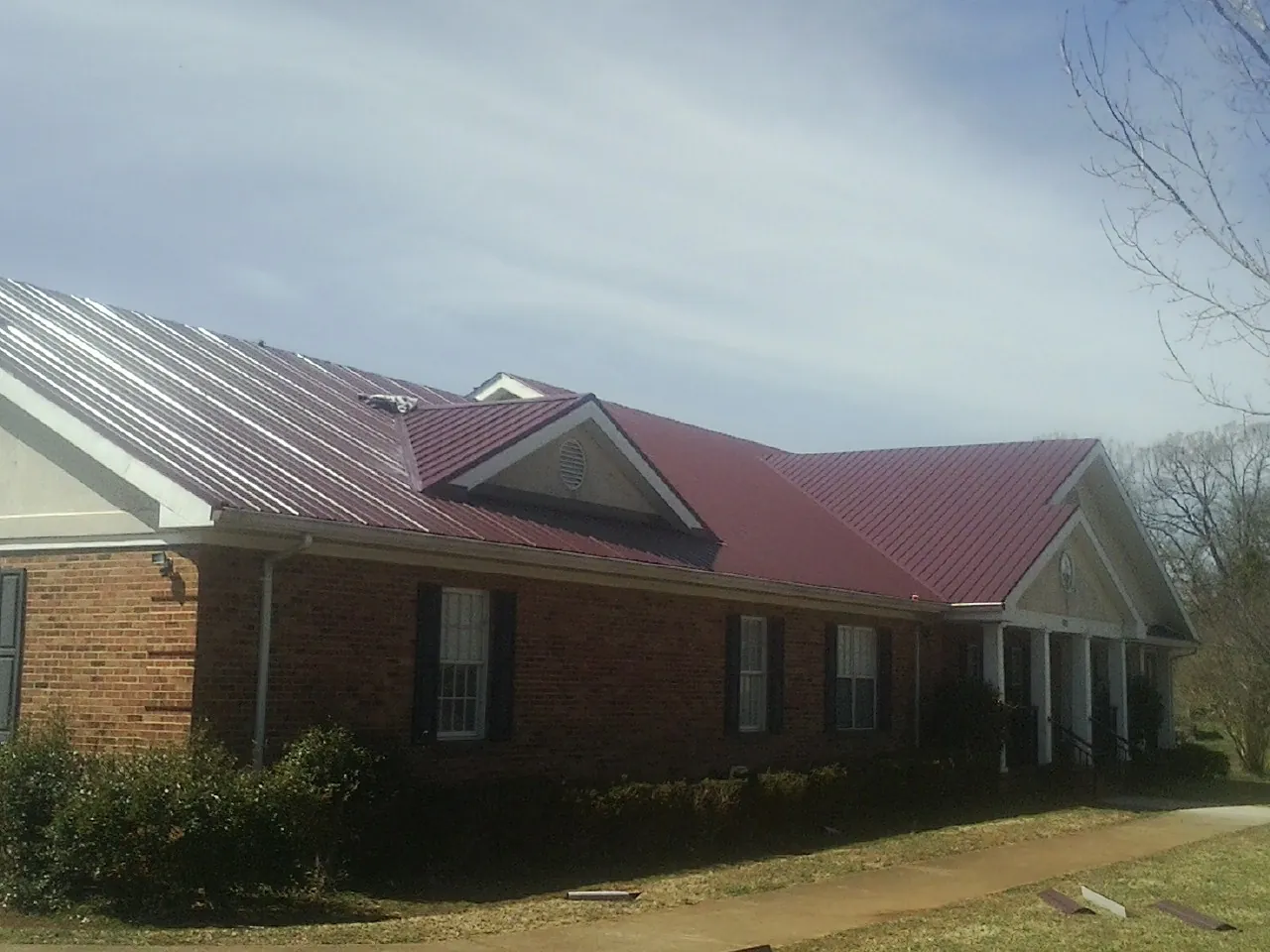Red metal roof with gabled entries on a long brick building, from a Hail Damage Roof Repair job in South Lake Tahoe