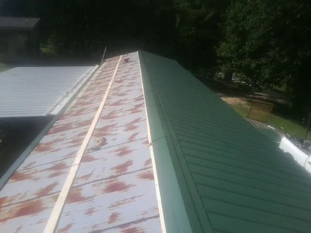 Old rusted panels beside newly installed green metal roofing — Wind Damage Roof Repair by Roofing Brothers in South Lake Tahoe