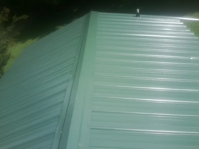 New green metal panels meeting at the ridge of a roof — Flat Roof Repair work by our crew in South Lake Tahoe