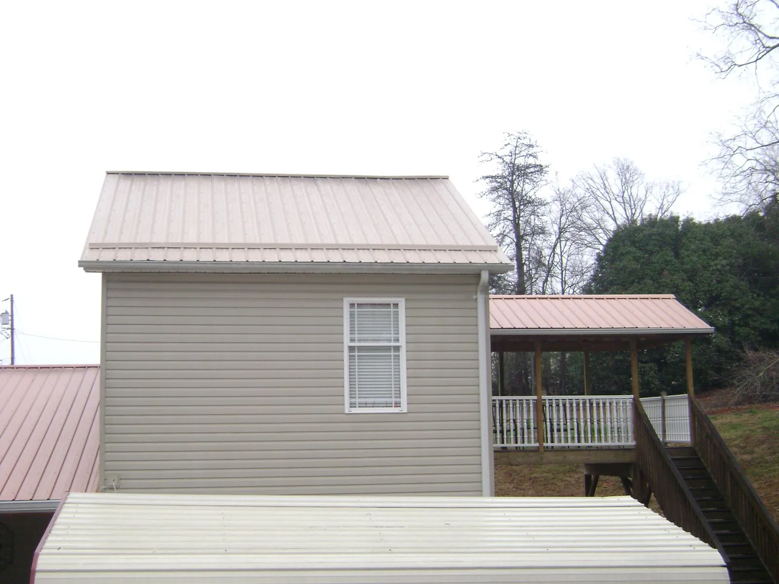 Tan metal roofs on a two story addition and attached porch, from a Roof Replacement job in South Lake Tahoe
