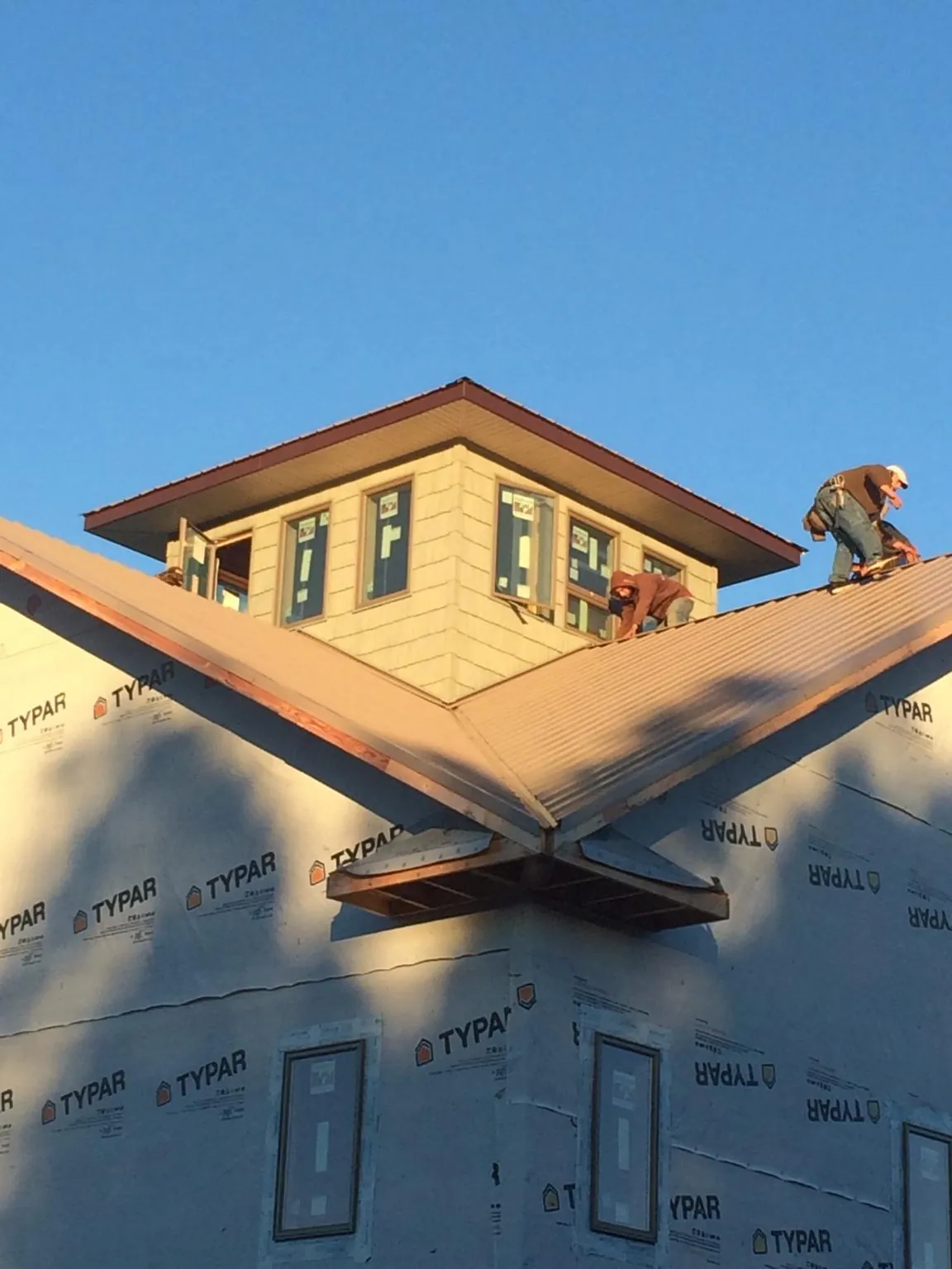Roofers working around a rooftop cupola on a new metal roof at sunset — Roof Waterproofing in South Lake Tahoe by Roofing Brothers